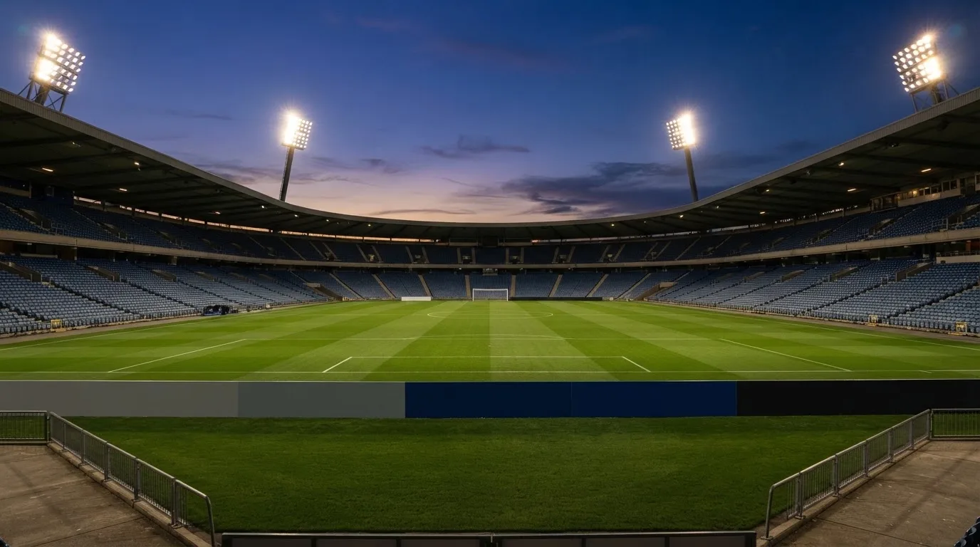 An empty football stadium with floodlight masts at dusk