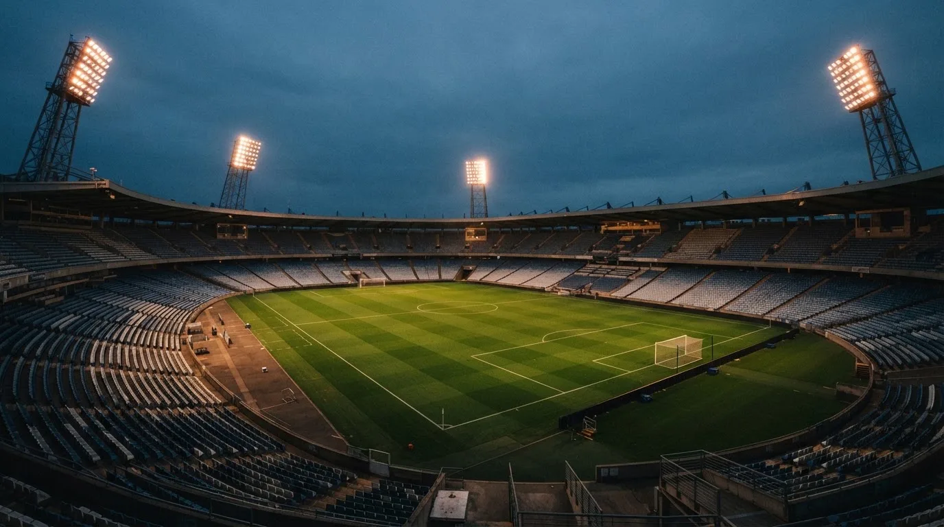 An empty football stadium with floodlight masts at dusk